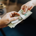 Two hands exchanging money symbolizing an education loan transaction