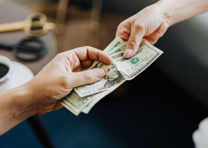 Two hands exchanging money symbolizing an education loan transaction