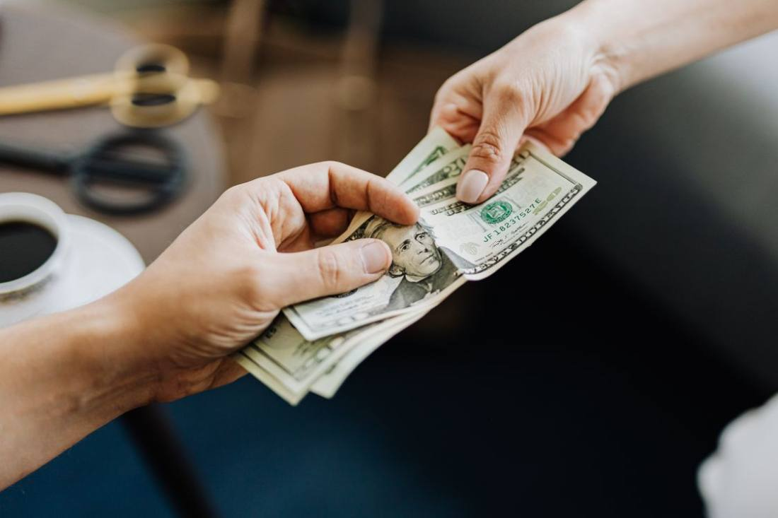 Two hands exchanging money symbolizing an education loan transaction