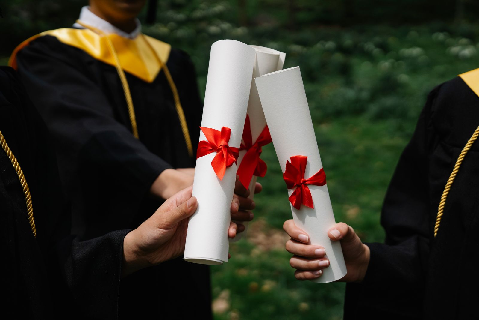 Graduates holding diplomas with red ribbons celebrating at an Irish university ceremony