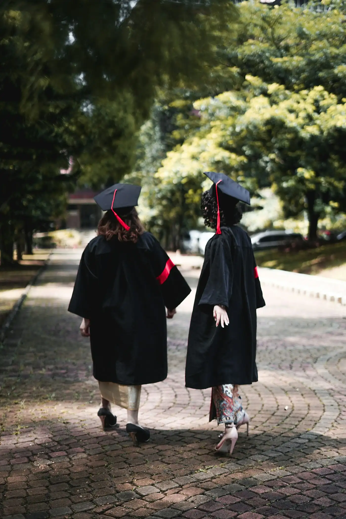 Two graduates walking across a campus in gowns