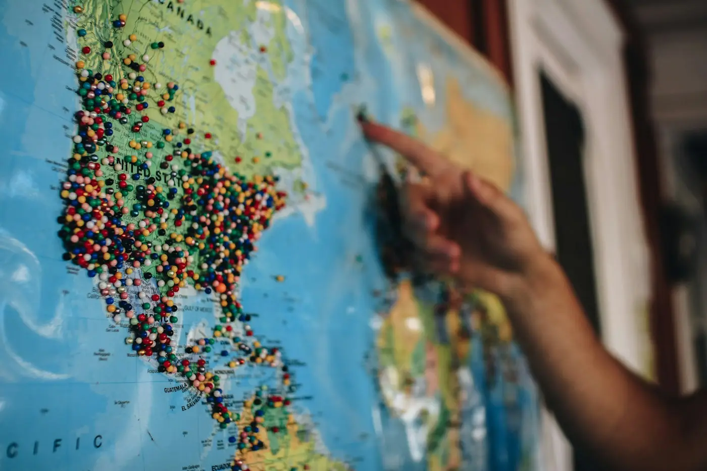 Hand pointing at a map full of pins while planning a study abroad shortlist