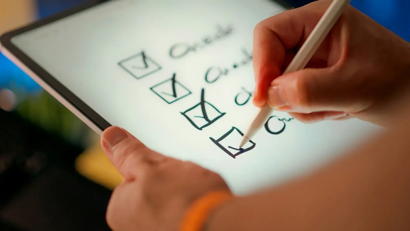 Ticking off a checklist on a tablet before finalising a university shortlist