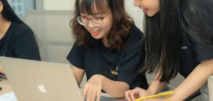 Which test for study abroad: two students comparing options on a laptop with a notebook