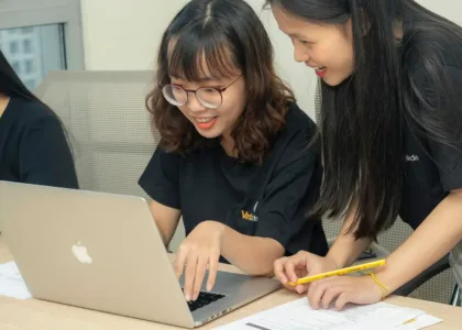 Which test for study abroad: two students comparing options on a laptop with a notebook